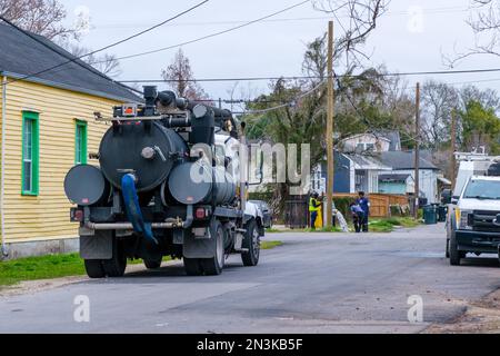 NEW ORLEANS, LA, USA - 1. FEBRUAR 2023: Stadtarbeiter stehen um einen offenen Hydranten inmitten der Stadt, die auch Servicefahrzeuge umfasst Stockfoto