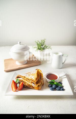 Süße Pfannkuchen mit Beeren und Honig auf einem weißen Teller, selektiver Fokus Stockfoto