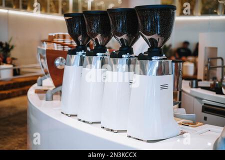 Frisch gemahlene Kaffeebohnen mit dieser geringen Tiefenschärfe weißer Kaffeemühlen in einem Café. Das Bokeh verleiht diesem Porträt oder dieser VE einen traumhaften Touch Stockfoto