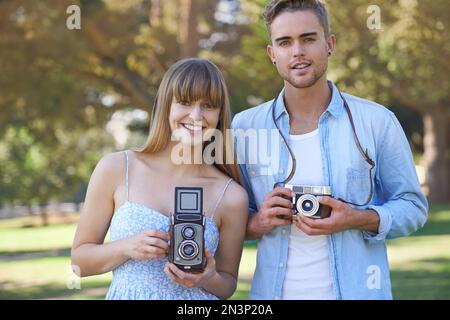 Liebe und Leidenschaft für Fotografie teilen. Ein junges Paar, das draußen Fotos mit alten Kameras macht. Stockfoto