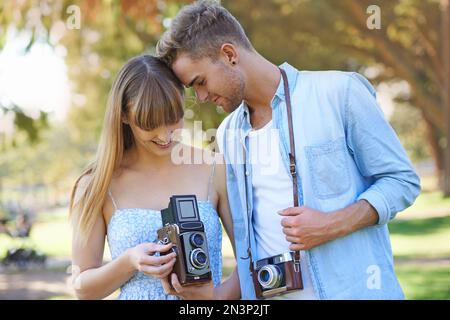 Liebe und Leidenschaft für Fotografie teilen. Ein junges Paar, das draußen Fotos mit alten Kameras macht. Stockfoto