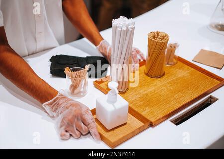 Ein minimalistisches Foto eines Holztabletts mit einem Glas Trinkhalme, das eine umweltfreundliche Option für Cafés und Restaurants darstellt Stockfoto