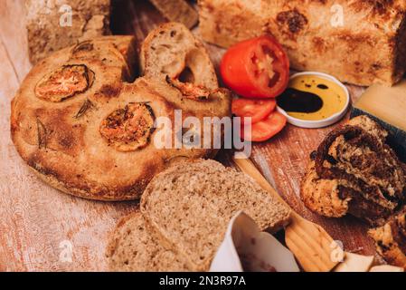 Eine Nahaufnahme von frisch gebackenem italienischem Brot mit anderen Zutaten auf dem Holztisch Stockfoto