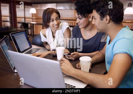 Dynamik der Studiengruppe. Eine Gruppe von Studenten, die einen Laptop verwenden, um eine Gruppenaufgabe abzuschließen. Stockfoto