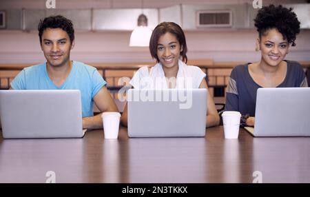 Dynamik der Studiengruppe. Eine Gruppe von Studenten, die einen Laptop verwenden, um eine Gruppenaufgabe abzuschließen. Stockfoto