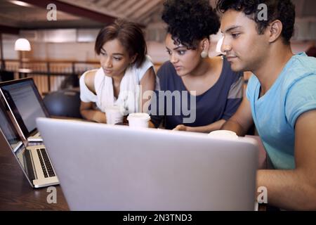 Dynamik der Studiengruppe. Eine Gruppe von Studenten, die einen Laptop verwenden, um eine Gruppenaufgabe abzuschließen. Stockfoto