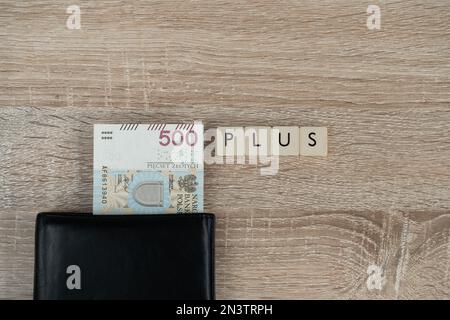 500 polnische Zloty-Banknote in einem Geldbeutel und Wort plus. Family 500+-Programm in Polen. Staatliche Hilfe für Kinder, soziale Hilfe bei der Kindererziehung. Stockfoto