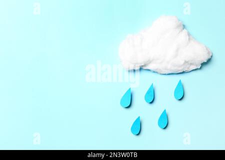 Weiße Baumwollwolke und Papiertropfen imitieren Regen auf cyanfarbenem Hintergrund, flach liegend. Platz für Text Stockfoto