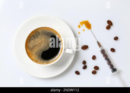 Tasse Kaffee und Spritze mit Bohnen auf weißem Hintergrund, flach liegend. Koffeinsuchtbegriff Stockfoto