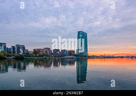 Europäische Zentralbank EZB, vor ihr die Sommerwerft und Wohnungen, Sonnenaufgang und Reflexion an den Ufern von Main, Frankfurt am Main, Hessen Stockfoto