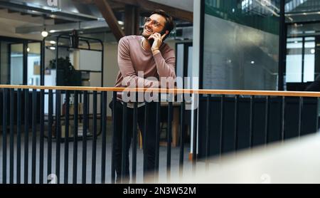 Geschäftsmann, der ein Gespräch auf einem Mobiltelefon in einem Büro führt. Männlicher Profi, der Klienten auf einem Handy anruft. Kommunikation und Vernetzung in t Stockfoto