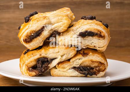 Seitlicher Haufen dänischen Gebäckstücks mit Schokoladenfüllung und Schokoladenchips auf weißer Keramikschale Stockfoto