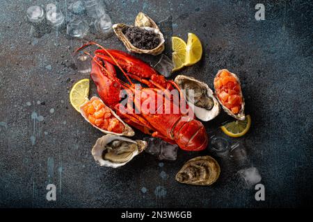 Gemischter Fisch- und Meeresfrüchteteller mit gekochtem roten Hummer, frischen offenen Austern, schwarzem Kaviar, Lachs-Tartare, serviert mit Zitronenspalten und Eiswürfeln Stockfoto