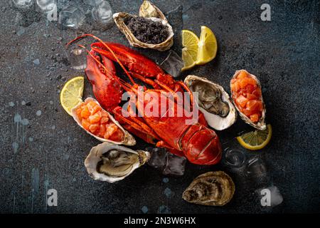 Gemischter Fisch- und Meeresfrüchteteller mit gekochtem roten Hummer, frischen offenen Austern, schwarzem Kaviar, Lachs-Tartare, serviert mit Zitronenspalten und Eiswürfeln Stockfoto