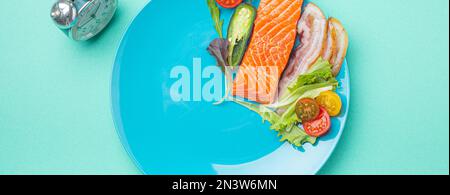 Intermittierendes Fasten Low Carb High Fats Diät-Konzept flach legen, gesunde Lebensmittel Lachs Fisch, Speck Fleisch, Gemüse und Salat auf blauem Teller und Uhr Stockfoto