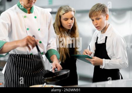 Die Schüler lernen Kochen in einem kulinarischen Institut mit Standardküche und kompletter Ausstattung. Und einen professionellen Koch als Trainer. Stockfoto