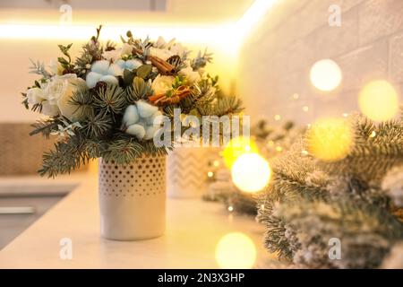 Wunderschöner Winterstrauß und Tannenzweige auf weißem Tisch im Innenbereich Stockfoto