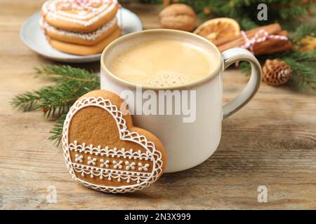 Leckerer herzförmiger Lebkeks und heißes Getränk auf einem Holztisch Stockfoto