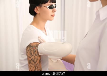 Junge Frau, die sich einer Lasertätowierung im Salon unterziehen muss Stockfoto