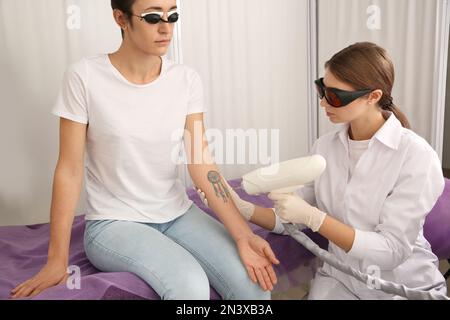 Junge Frau, die sich einer Lasertätowierung im Salon unterziehen muss Stockfoto