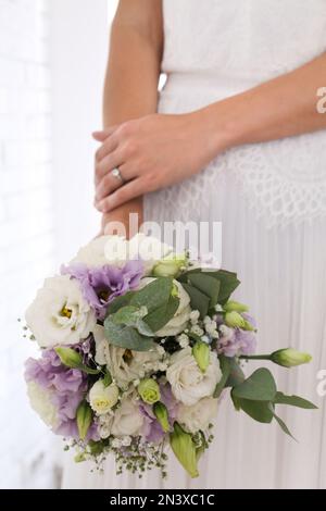 Die Braut hält einen wunderschönen Strauß mit Eustoma-Blumen drinnen, Nahaufnahme Stockfoto