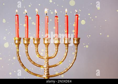 Menorah mit brennenden Kerzen auf farbigem Hintergrund, Nahaufnahme. Hanukka-Feier Stockfoto