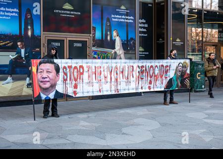 Stoppt den uigurischen Völkermord! Männer mit einem Banner mit Bild von Xi Jinping auf Keskuskatu in Helsinki, Finnland. Stockfoto