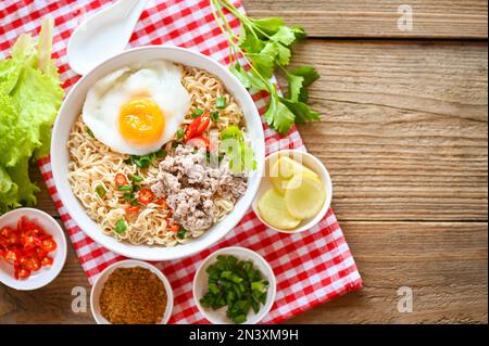 instant-Nudeln kochen leckeres Essen mit Schüssel, Nudelschüssel mit gekochtem Ei Hackfleisch Schweinefleisch Gemüse Frühlingszwiebeln Zitronen Limetten Salat Sellerie und Chili on Stockfoto