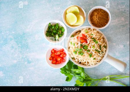 instant Nudeln kochen lecker essen mit Schüssel, Nudelschüssel mit Gemüse Frühlingszwiebeln Zitronen Limetten Salat Sellerie und Chili auf dem Tisch, Nudelsou Stockfoto