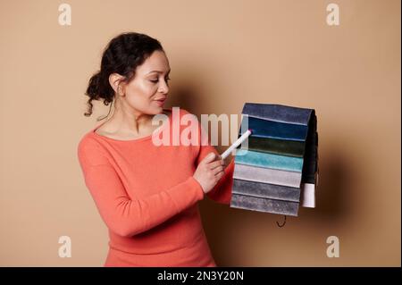 Selbstbewusste Innendesignerin im Möbelgeschäft, die vor der Kamera eine große Palette an Polstermaterialien präsentiert Stockfoto