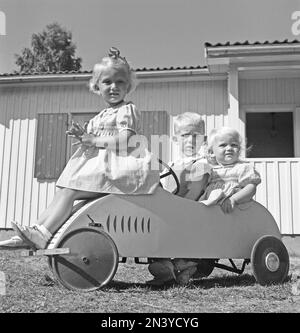 Tretwagen in der 1940er. Drei Kinder, die an einem Sommertag in einem Tretwagen spielen. Schweden 1947 Kristoffersson Ref U135-5 Stockfoto