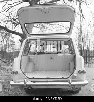 Fahren in der 1960er. Ein Paar sitzt in seinem Auto, einem Opel Olympia, einem praktischen Auto mit Platz im Kofferraum, der bei geöffneter Hintertür zu sehen ist. Schweden 1961 Kristoffersson Ref CT49-7 Stockfoto