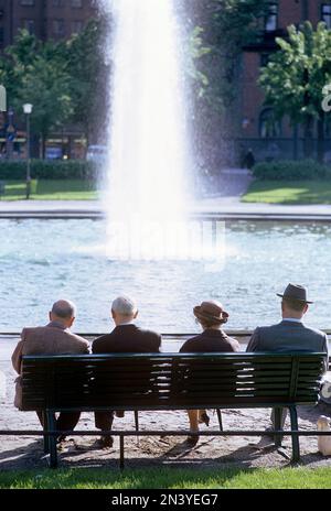 In den 1960er Jahren. Eine Gruppe von vier älteren Menschen sitzt auf einer Bank mit Blick auf einen Brunnen. Schweden Juli 1967 Kristoffersson CV52-6 Stockfoto