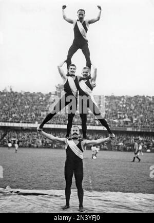 Gleichgewicht und Stärke. Vier Männer in einem Akt, die während eines Fußballspiels um ein großes Publikum bitten. Der stärkste am Boden balanciert die drei auf seinen Schultern und Armen. Schweden 1930er Stockfoto