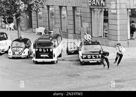 Der Norrmalmstorg-Raub am 23-28. august 1973. Kreditbanken auf der Normmalmstorg in Stockholm. Das erste kriminelle Ereignis in Schweden, über das live im Fernsehen berichtet wurde. Jan-Erik Olsson war der Räuber und wurde von einem ehemaligen Zellengenossen und Freund Clark Olofsson in der Bank begleitet. Die Räuber gaben auf, nachdem die Polizei Tränengas benutzte, keiner der Geiseln wurde verletzt. Ein Banküberfall und eine Geiselnahme, am besten bekannt als der Ursprung des Wortes Stockholm-Syndrom, ein vorgeschlagener Zustand, in dem Geiseln eine physologische Bindung zu ihren Entführern entwickeln. Das Bild zeigt die Polizeiautos vor der Bank, Ford, Volkswa Stockfoto