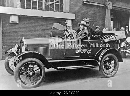 Ford Geschichte. Der fünfzehnmillionste Ford-Wagen ist bereit. Die Veranstaltung ist geprägt von Henry Ford und seinem Sohn Edsel, die im Auto zu sehen sind, wenn es sich außerhalb der Produktionslinie im Ford-Automobilwerk 1927 befindet. Stockfoto