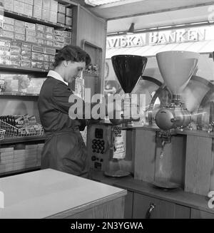 In den 1950er Jahren. Eine Frau, die in einem Geschäft arbeitet, wird dabei gesehen, wie sie Kaffeebohnen in eine Papiertüte mahlt. Schweden 1958 Ref. BV100-5 Stockfoto