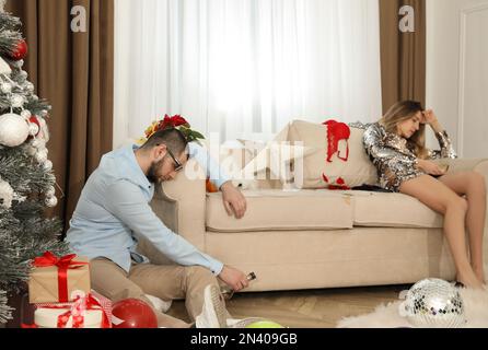 Leute, die nach der Silvesterparty einen Kater in einem chaotischen Zimmer haben Stockfoto