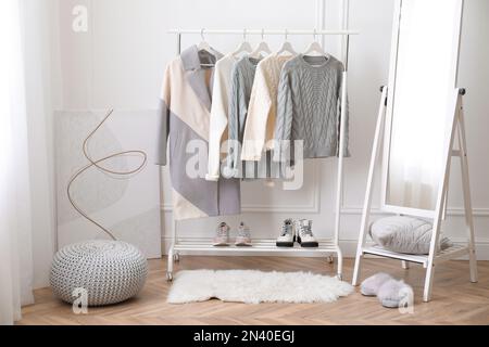 Ablage mit stilvoller warmer Kleidung und Spiegel im Ankleidezimmer Stockfoto