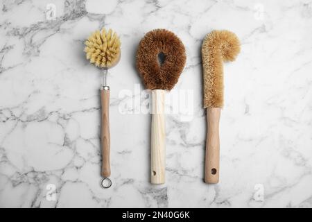 Reinigungsbürsten zum Geschirrspülen auf weißem Marmortisch, flach liegend Stockfoto