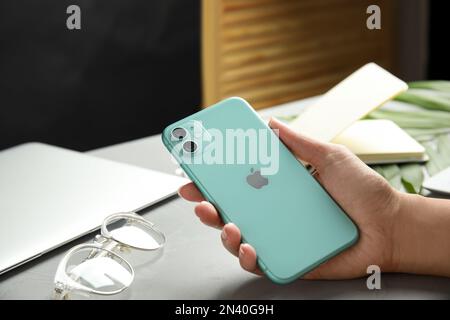 MYKOLAIV, UKRAINE - 9. JULI 2020: Frau mit iPhone 11 Green am Tisch, Nahaufnahme Stockfoto