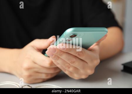 MYKOLAIV, UKRAINE - 9. JULI 2020: Frau mit iPhone 11 Green am Tisch, Nahaufnahme Stockfoto