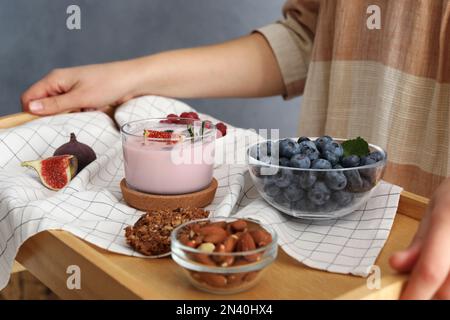 Eine Frau hielt ein Holztablett mit köstlichem Frühstück und FeigenSmoothie, Nahaufnahme Stockfoto