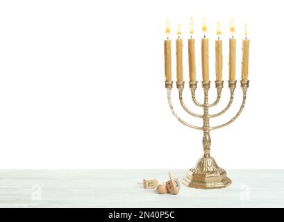 Goldene Menorah und Hanukka dreidels mit He-, Gimel-, Nun-Symbolen auf weißem Hintergrund Stockfoto