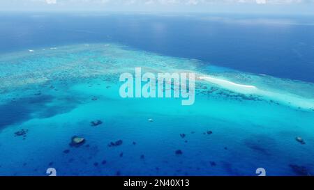 Kleine sandkai mit einer abgelegenen Wetterstation umgeben von einem Riff im Korallenmeer vor Australien mit einem Segelboot in der Lagune Stockfoto