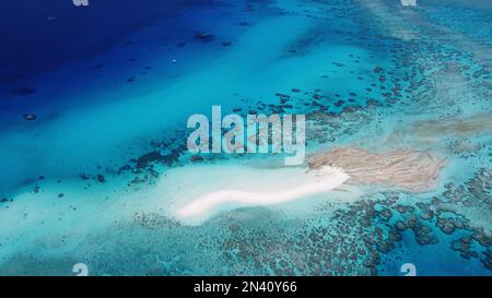 Kleine sandkiste mit einer abgelegenen Wetterstation umgeben von einem Riff im Korallenmeer vor Australien mit einem Segelboot in der Nähe Stockfoto