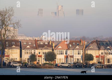 Ein Läufer joggt vorbei an edwardianischen Häusern, die an den Ruskin Park Grenzen, und der Morgennebel verdeckt teilweise Hochhäuser in der Ferne von Nine Stockfoto