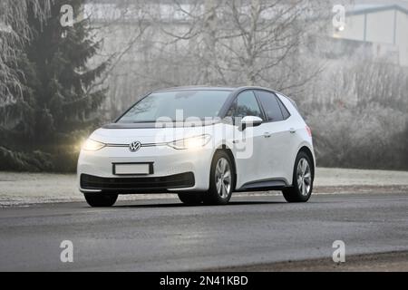 Weißer Volkswagen ID3 Elektroauto, der an einem nebligen Wintertag auf der Straße fährt. Salo, Finnland. 21. Januar 2023 Stockfoto