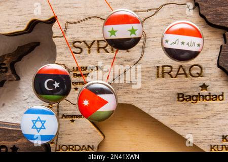 Syrien, Irak, Israel, Libanon, Iran-Flaggen auf den Stecknadeln und roter Faden auf der hölzernen Karte, Nahaufnahme. Logistikrouten und geopolitisches Konzept. Stockfoto