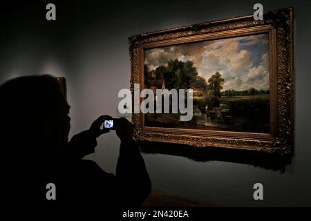 A woman takes pictures of 'The Hay Wain' by British landscape painter John Constable, during a preview of an exhibition entitled: 'Constable: The Making of a Master ' with works by the artist at the Victoria and Albert Museum, in London, Wednesday, Sept. 17, 2014. Best-known to many for ‘The Hay Wain’ - an artwork which adorns countless decorative plates and trays, the exhibition explores Constable’s influences and takes a look at the creative process behind some of his most famous works. The exhibition will run from Sept. 20, 2014 to Jan. 11. 2015.(AP Photo/Lefteris Pitarakis)